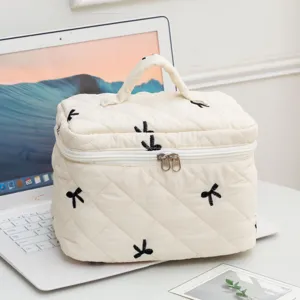 Cream quilted makeup bag with black embroidered bows, large capacity and top handle.