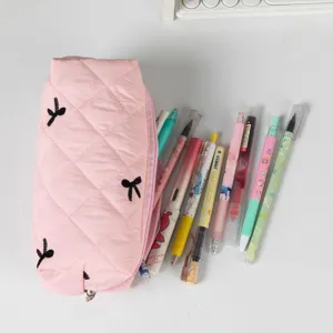 Close-up of pink quilted pencil case with black bow embroidery and various pens