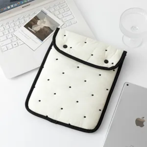 Vista detallada de la funda acolchada para portátil con lunares en escritorio