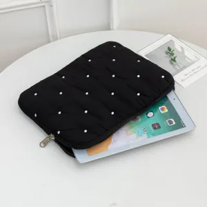 Detail of black quilted tablet sleeve with white polka dot embroidery showing interior