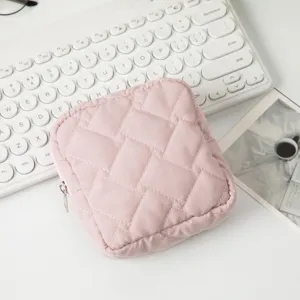 Detailansicht einer gesteppten rosa quadratischen Kosmetiktasche auf dem Schreibtisch