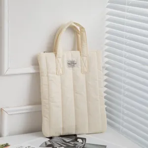 Ästhetische Lifestyle-Ansicht einer cremefarbenen gesteppten Laptoptasche im Raum