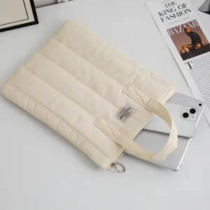 Detailansicht eines Tablets, das in eine cremefarbene gesteppte Laptoptasche gesteckt wird.