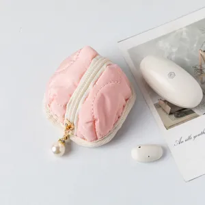 Close-up of pink quilted cotton pouch with elegant pearl zipper pull on white surface