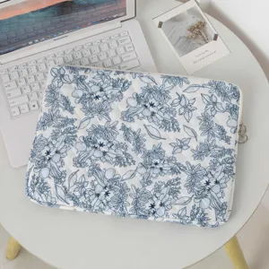 Gros plan d'une housse d'ordinateur portable matelassée à fleurs bleues sur un bureau
