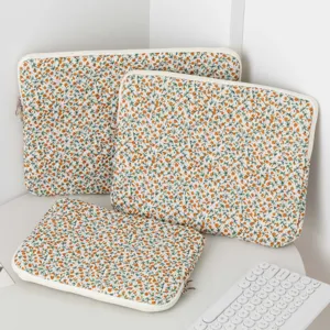 Detailed macro view of three quilted floral laptop sleeves set on a clean white desk