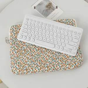 Detail of a quilted floral laptop sleeve with a white wireless keyboard on top.