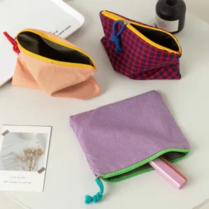 Nahaufnahme von drei bunten karierten Stoff-Kosmetiktaschen auf einem minimalistischen Tisch