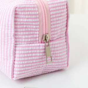 Nahaufnahme der rosa gestreiften Seersucker-Kosmetiktasche mit silbernem Reißverschluss