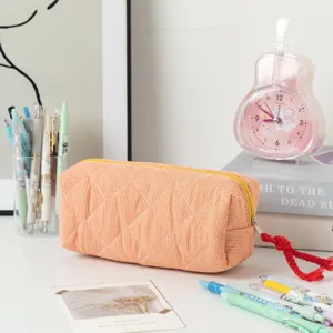 Vista dettagliata dell'astuccio trapuntato a quadretti arancioni con zip gialla.