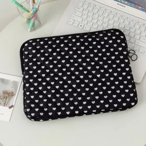 Κομψή μαύρη καπιτονέ θήκη για laptop με λευκά σχέδια καρδιάς σε ένα σύγχρονο γραφείο.