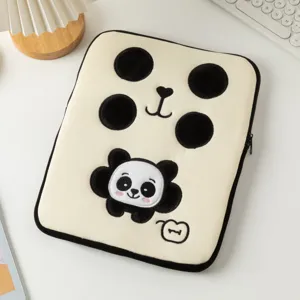 Détail rapproché du motif panda brodé sur une housse d'ordinateur en peluche crème.