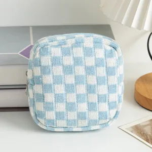 Gros plan d'une pochette cosmétique en tricot à damier bleu clair sur un bureau blanc.
