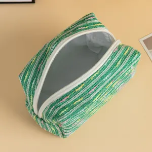 Dettaglio di una borsa per trucchi a righe verdi con grande capacità interna e cerniera