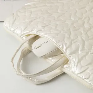 Close-up detail of cream white quilted heart pattern laptop bag with mouse inside.