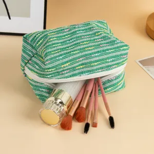Vista dettagliata della borsa cosmetica a righe verdi con pennelli da trucco e accessori