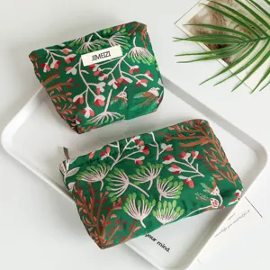 Set of two green floral makeup bags on a white tray with fresh plant accent