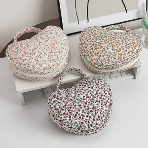 Ein Trio herzförmiger gesteppter Kosmetiktaschen mit vielen zarten Blumenmustern
