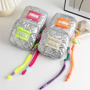 Close-up of four silver quilted PU cosmetic bags with colorful braided zipper pulls