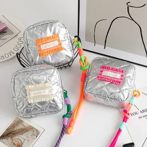 Detail view of silver PU mini square bags with heart patterns and colorful braided straps