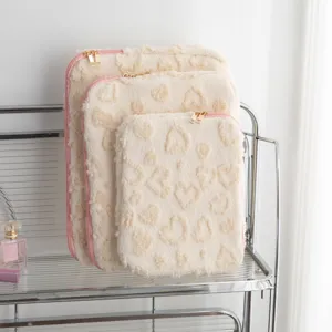 Detail view of plush heart-patterned laptop and tablet sleeves shown in three sizes
