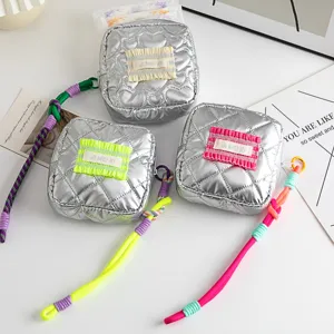 Detailed view of silver quilted PU pouches with colorful ruffles and braided zipper pulls