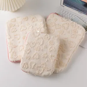 Close-up view of three beige plush heart-patterned laptop sleeves for iPad and Pro