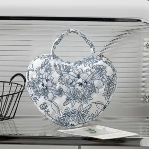 Detailansicht des blauen Blumenmusters und der Stepptextur auf einer herzförmigen Tasche