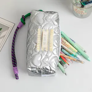 Detail view of large silver quilted pencil case showing heart patterns and interior capacity