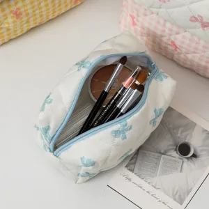 Vista dettagliata di una borsa da trucco trapuntata portatile con fiocchi blu e pennelli