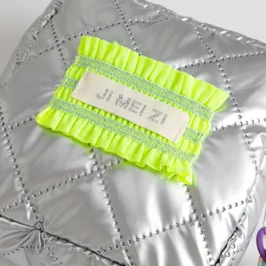 Close-up detail of metallic silver quilted PU makeup bag with neon green patch