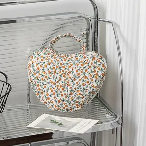 Herzförmige gesteppte Kosmetiktasche mit floralem Muster auf einem modernen Regal