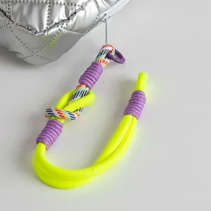 Close-up of bright neon yellow rope handle on silver quilted waterproof cosmetic bag