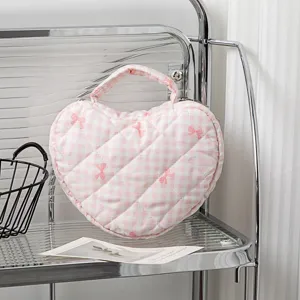 Detailansicht der herzförmigen, gesteppten Kosmetiktasche mit rosa Karo- und Schleifenmuster.
