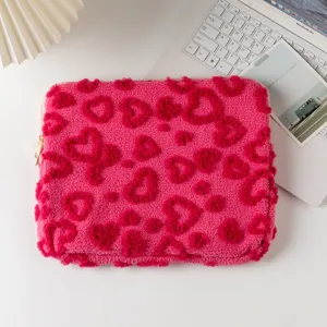 Pink plush laptop sleeve with soft heart embossed pattern on a white work desk
