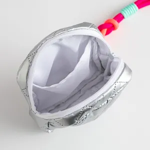 Interior detail of a silver quilted PU makeup bag with white lining and pocket.
