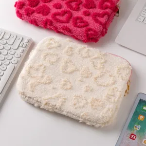 Detail of cream plush tablet sleeve with textured heart patterns and gold zipper closure.