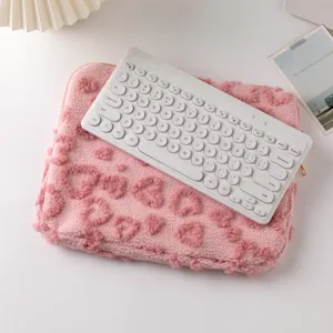 Detail view of plush pink laptop sleeve with heart pattern and white keyboard prop