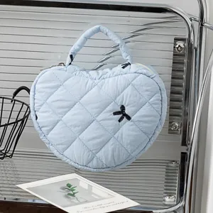 Detailansicht der hellblauen herzförmigen gesteppten Kosmetiktasche im Regal.