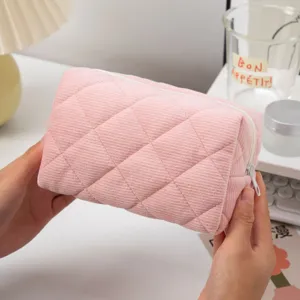 Detailed macro view of a pink quilted corduroy cosmetic storage bag held in hands