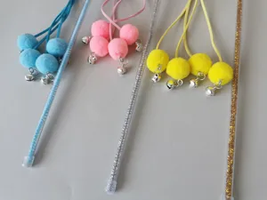 Close-up detail of interactive cat teaser wand with transparent PVC stick, plush balls, and bells.