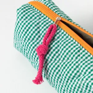 Primo piano dell'astuccio a quadretti verdi con zip arancione e tiretto in corda rosa