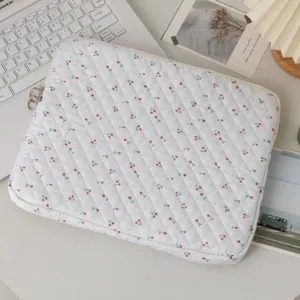 Κοντινή λήψη καπιτονέ λευκής θήκης laptop με χαριτωμένο σχέδιο κεράσι και ραφές διαμάντι