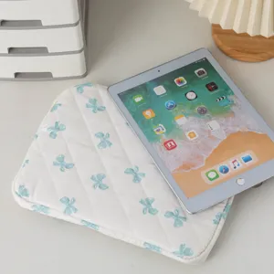 Μακρο λεπτομέρεια λευκής καπιτονέ θήκης iPad με μπλε σχέδια φιόγκων σε γραφείο εργασίας
