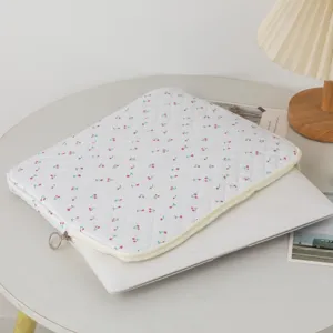 Λεπτομέρεια καπιτονέ θήκης laptop με κεράσια σε γραφείο δίπλα σε επιτραπέζιο φωτιστικό