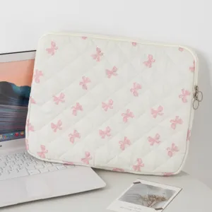 Καπιτονέ θήκη iPad με ροζ φιόγκους δίπλα σε φορητό υπολογιστή σε λευκό γραφείο.