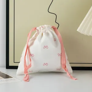 Detailed view of a sweet cream cotton drawstring pouch with pink bow pattern print.