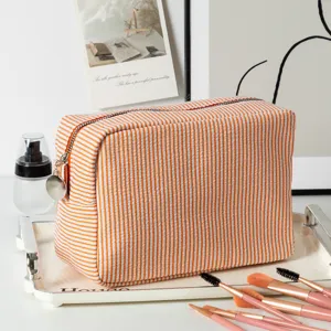 Detailed view of large orange striped seersucker travel makeup bag on vanity tray