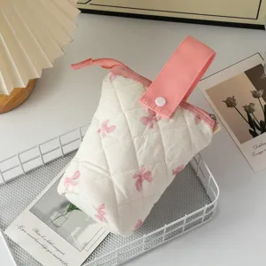 Détail d'une trousse souple matelassée avec motifs nœuds roses et une poignée à bouton
