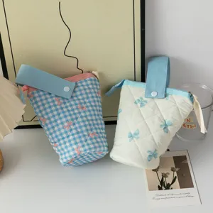 Vue de deux trousses en tissu esthétiques avec motifs de nœuds et sangles de transport bleues